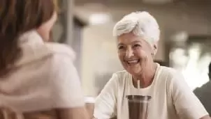 Mujer sonriendo mientras toma café